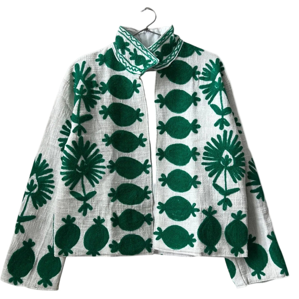 ront view of an open-style handmade white textured cotton TNT short jacket featuring bold, large-scale emerald green Suzani embroidery with floral and botanical motifs, isolated against a solid white background.