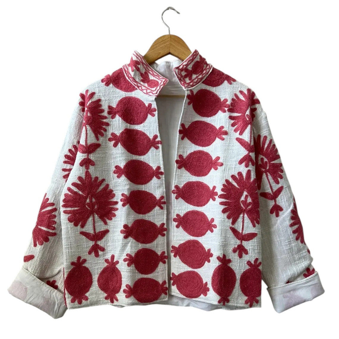 Front view of an open-style handmade white textured cotton TNT short jacket featuring bold, large-scale red Suzani embroidery with floral and pomegranate-like botanical motifs, isolated against a solid white background.