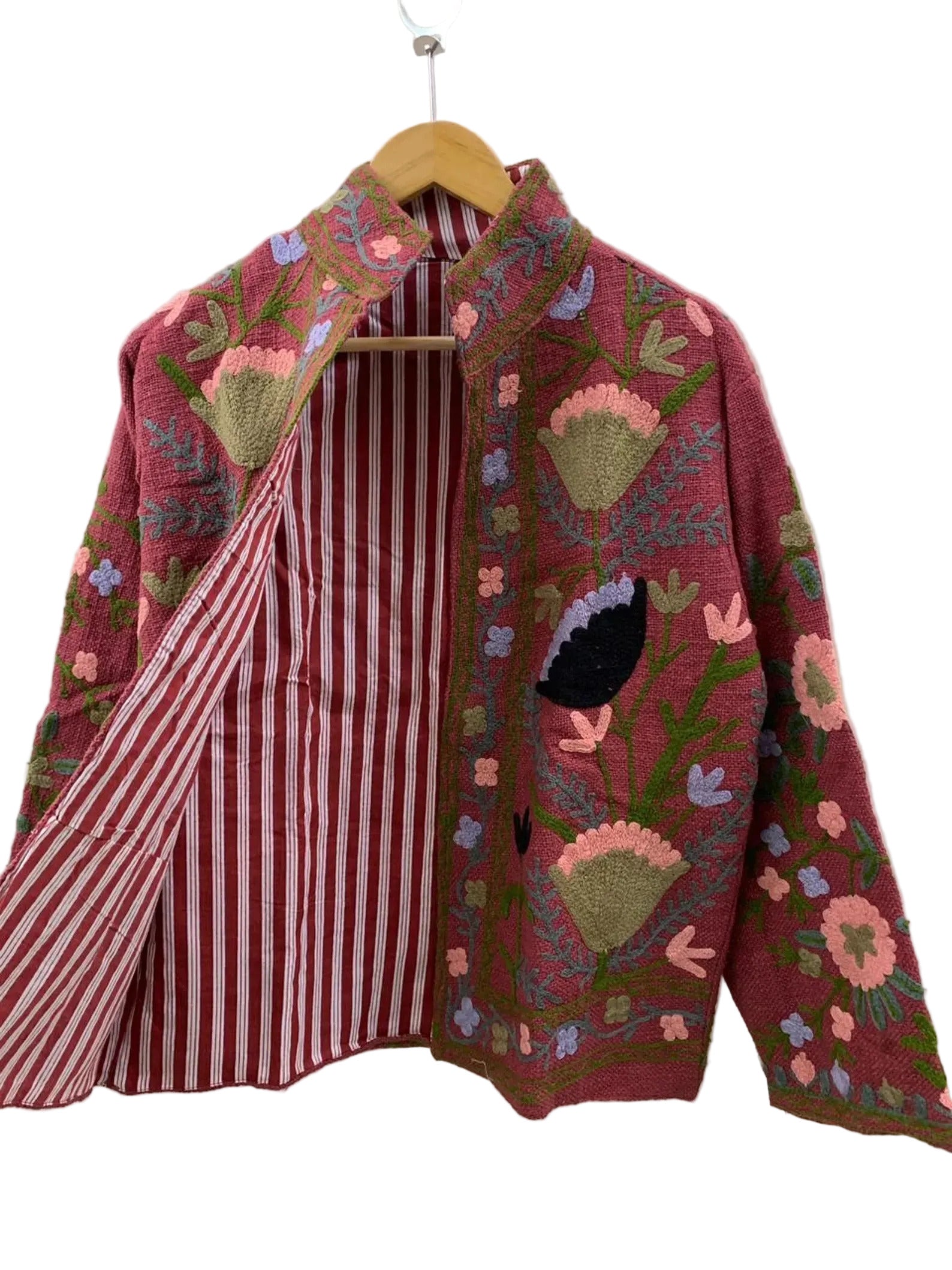 Colorful embroidered jacket on a hanger against a white background