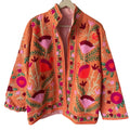 Front view of an open-style handmade orange textured cotton TNT jacket featuring vibrant pink and red Suzani floral embroidery with green vines, showcasing a red-and-white striped interior lining, isolated on a light background.