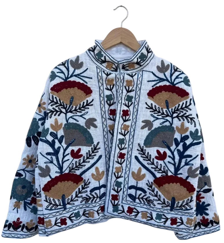 White textured TNT jacket featuring symmetrical hand-embroidered geometric flowers in deep red, mustard gold, and dark navy.