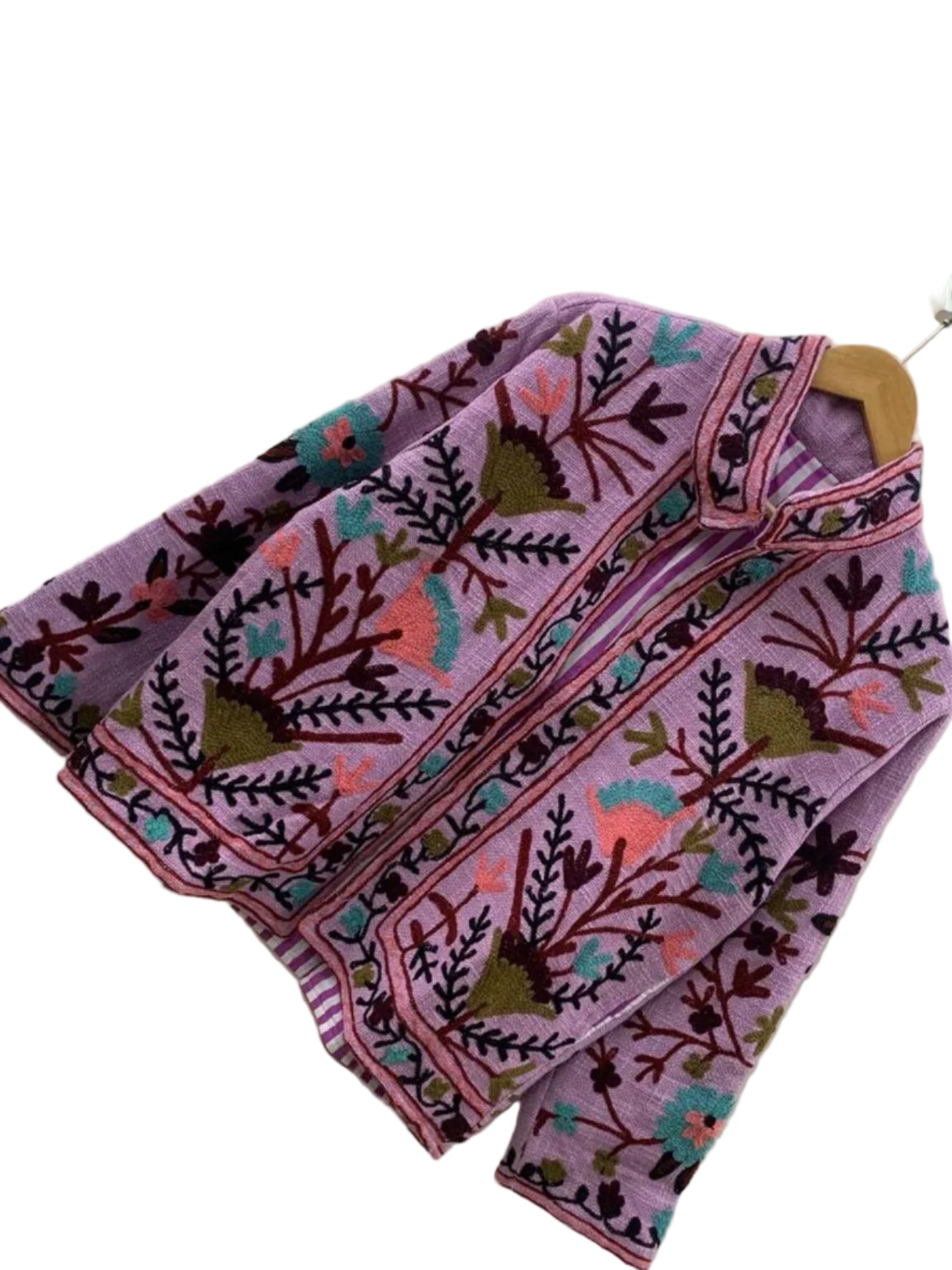 TNT jacket featuring teal, coral pink, and olive green Suzani floral embroidery, showcasing a purple-and-white striped interior lining, hanging on a wooden hanger against a white wall.