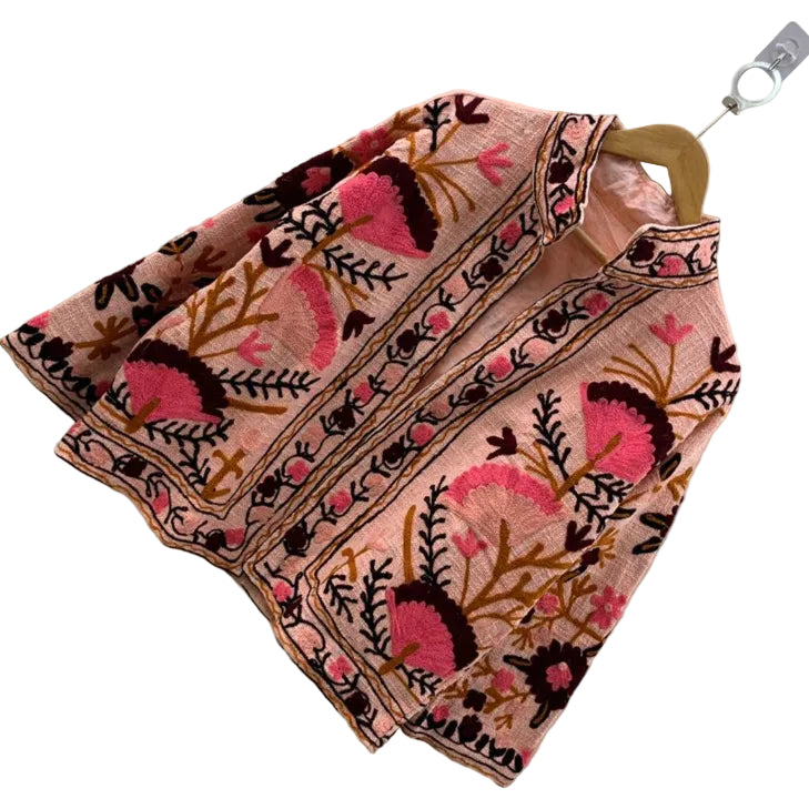 Front view of an open-style handmade peach pink textured cotton TNT short jacket featuring bright pink and dark maroon Suzani fan-floral embroidery with brown branches.