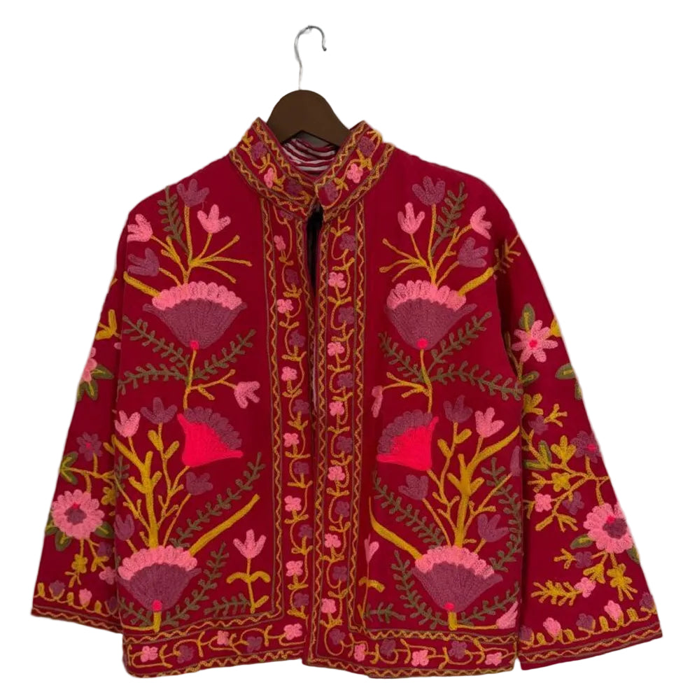 Deep red open-front TNT jacket featuring symmetrical pink, purple, and yellow floral embroidery with a detailed stitched border, hanging on a wooden hanger.