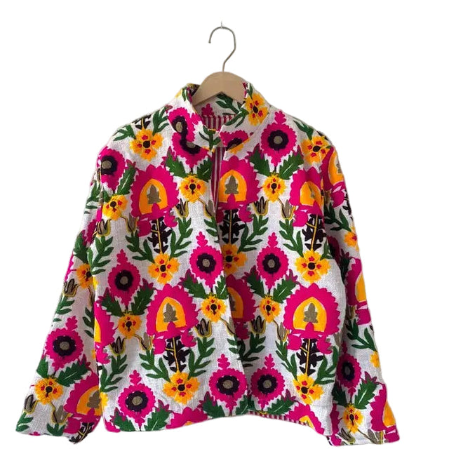 Front view of an open-style handmade white textured cotton TNT short jacket featuring a dense, all-over pattern of bright hot pink, yellow, and green Suzani floral embroidery.